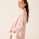 Woman wearing a light pink blouse with a white collar against a beige background