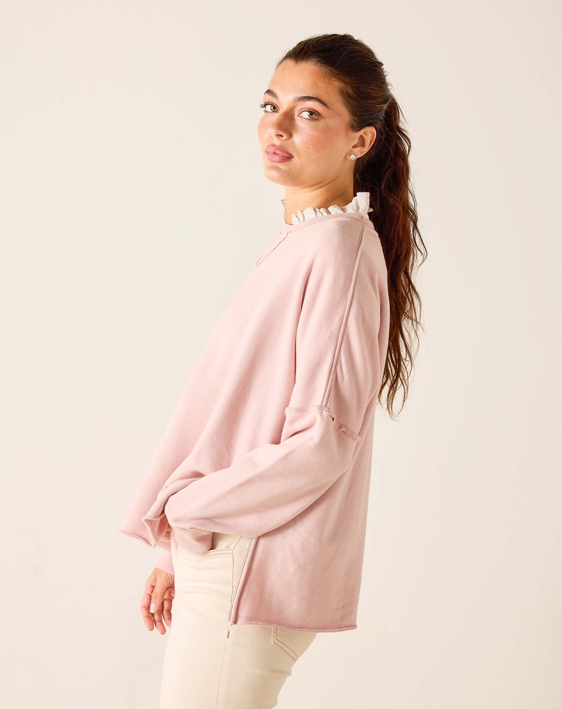Woman wearing a light pink blouse with a white collar against a beige background