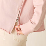 Close-up of a pink jacket with a zipper and beige pants on a light background