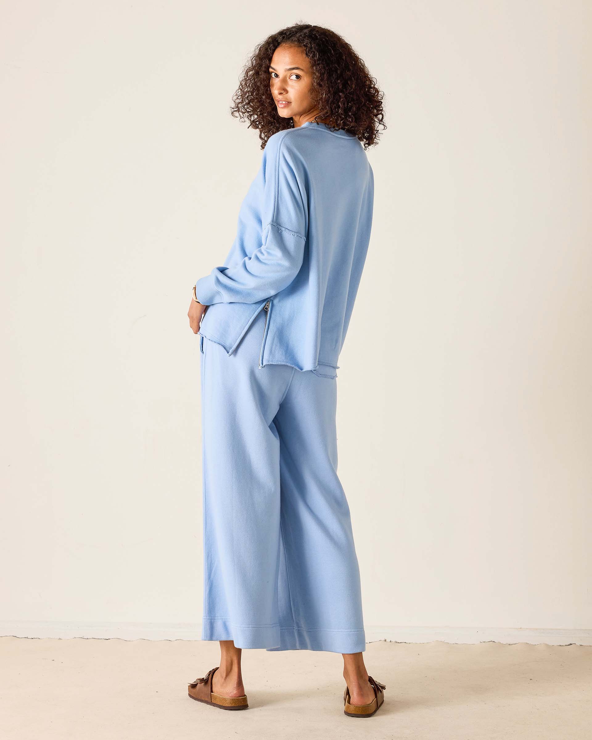 Woman wearing a light blue outfit against a plain background