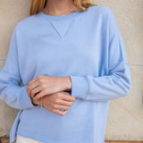 Person wearing a light blue sweater against a beige wall