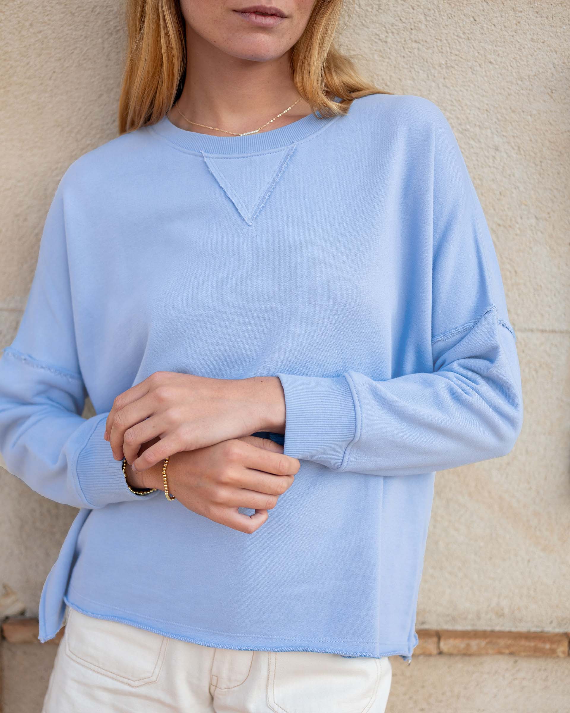 Person wearing a light blue sweater against a beige wall