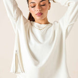 Woman wearing a white long-sleeve top with a plain background