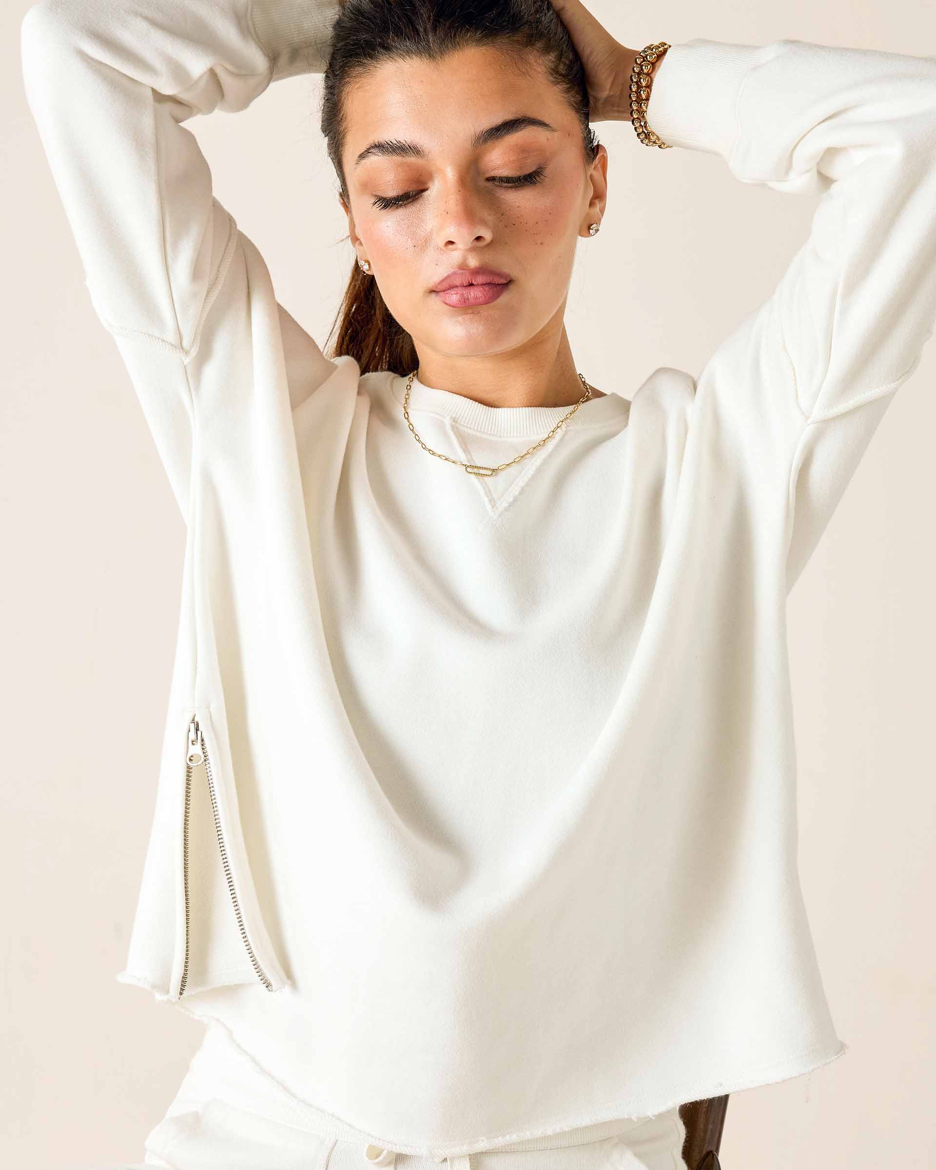 Woman wearing a white long-sleeve top with a plain background