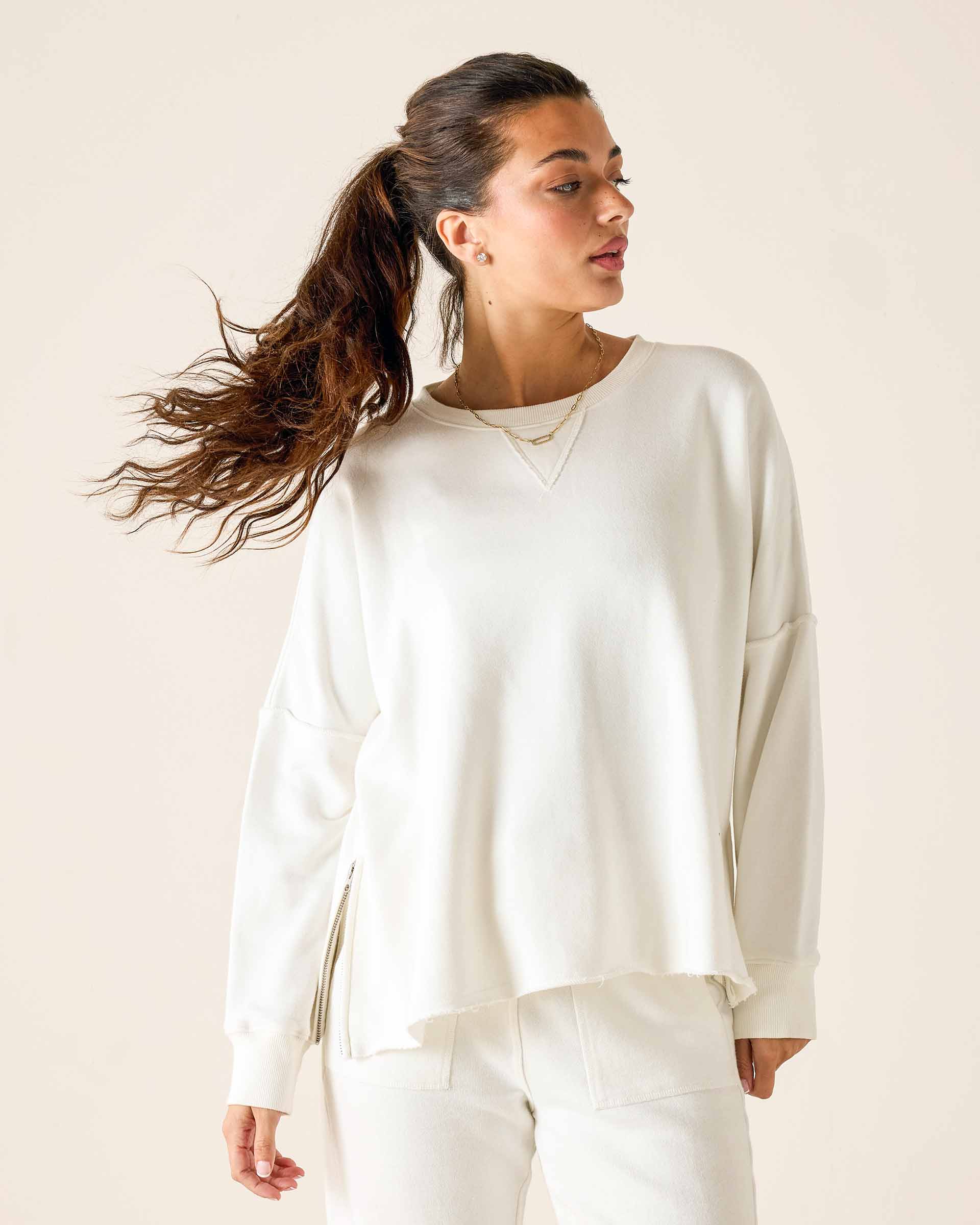Woman wearing a white sweatshirt against a plain background