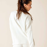 Woman wearing a white sweatshirt against a beige background