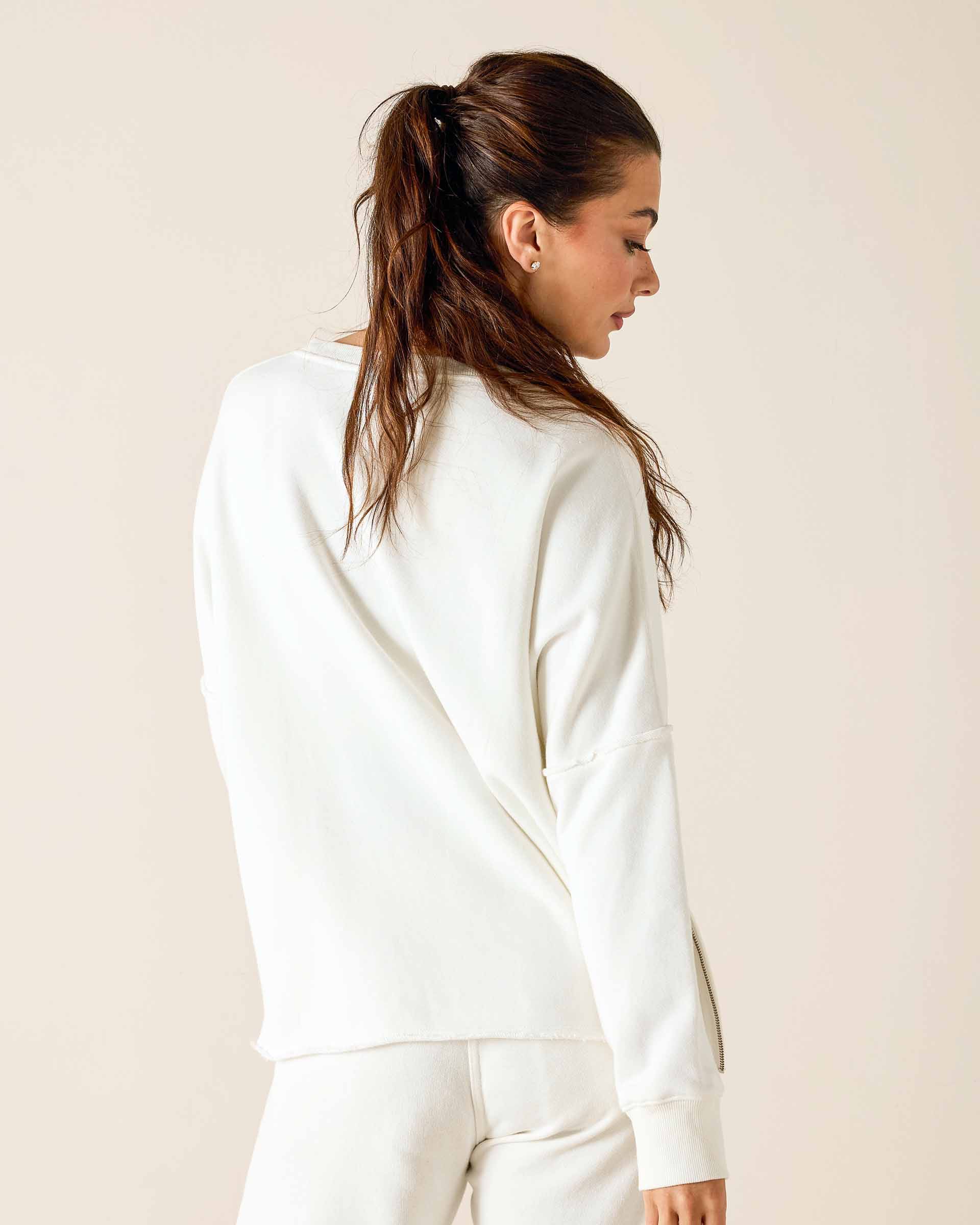 Woman wearing a white sweatshirt against a beige background