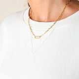 Gold chain necklace worn by a person on a plain background