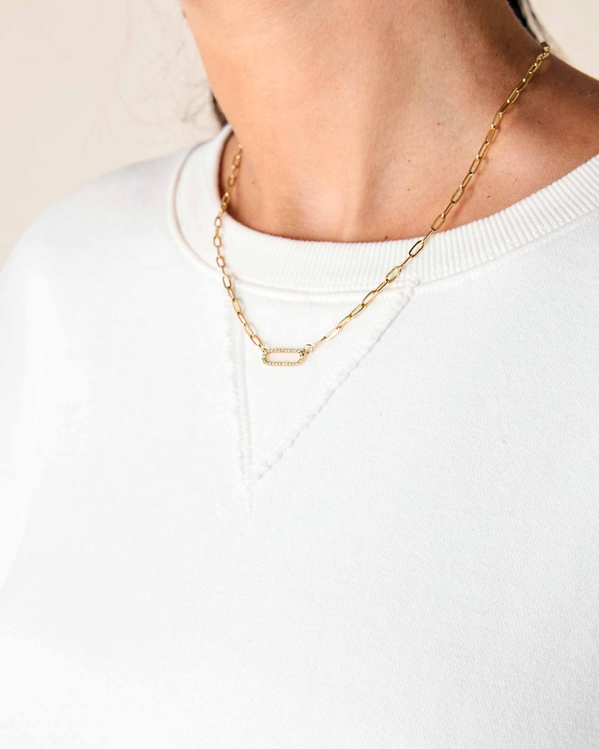 Gold chain necklace worn by a person on a plain background