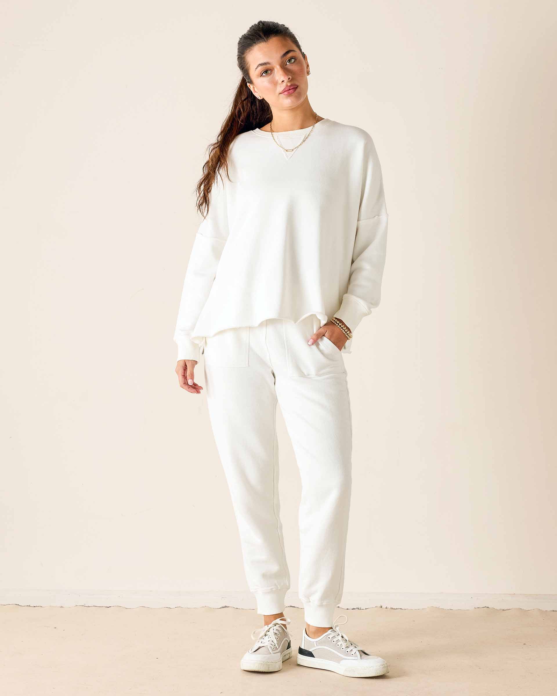 Person wearing a white outfit with sneakers against a plain background