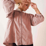 Blush pink button-down blouse with voluminous puff sleeves and button details.