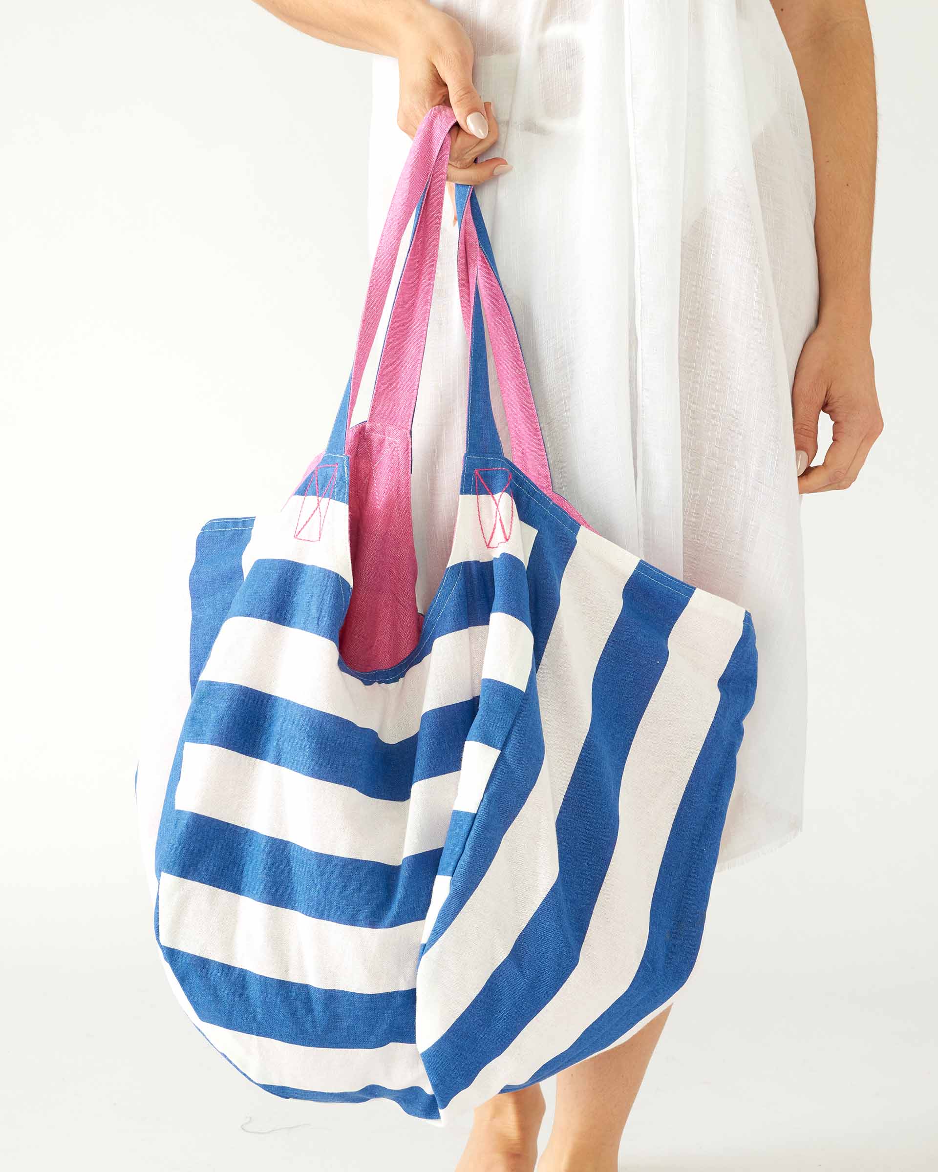 woman holding striped gemini reversible tote in hand