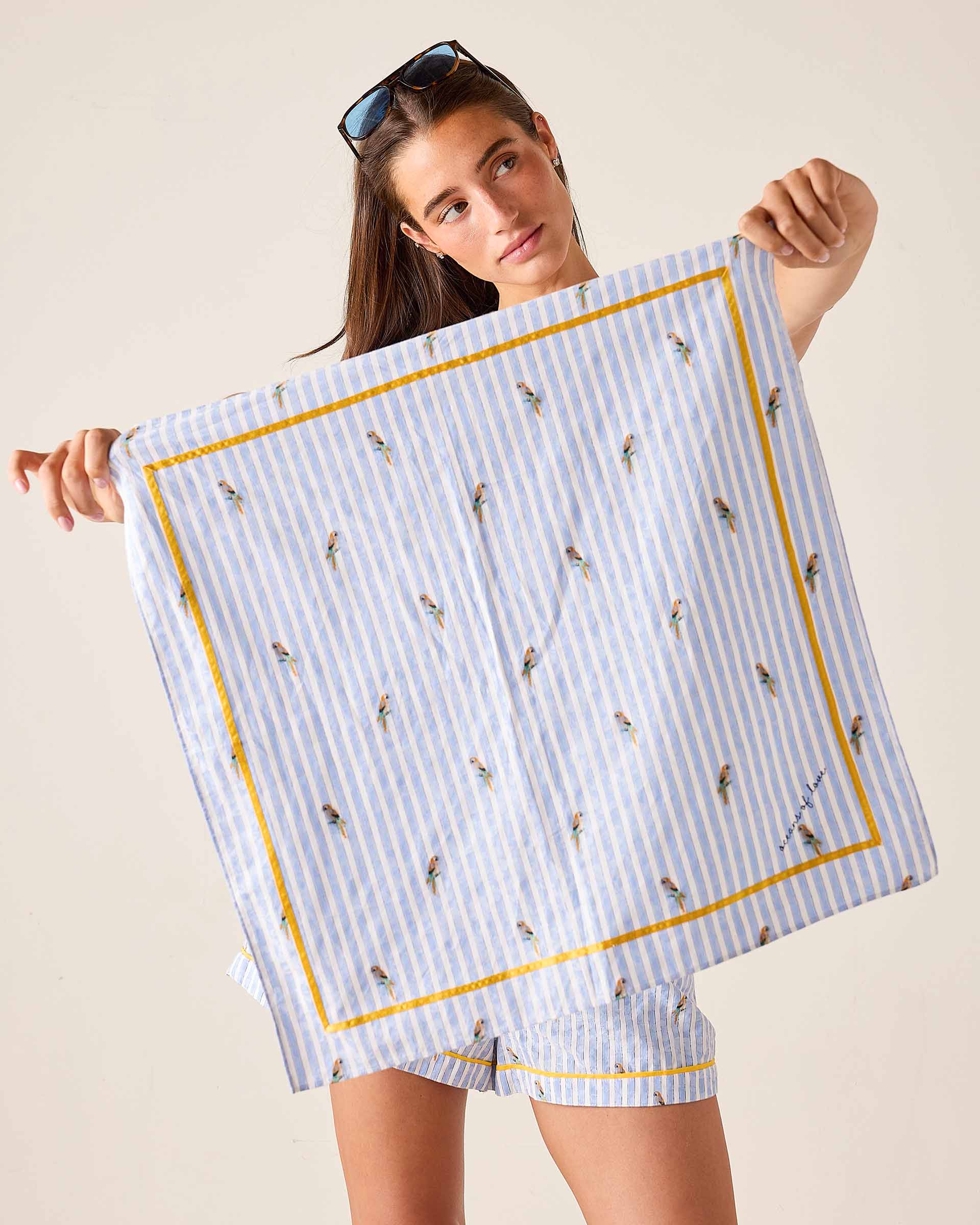 Woman holding a blue and white striped towel with bird pattern