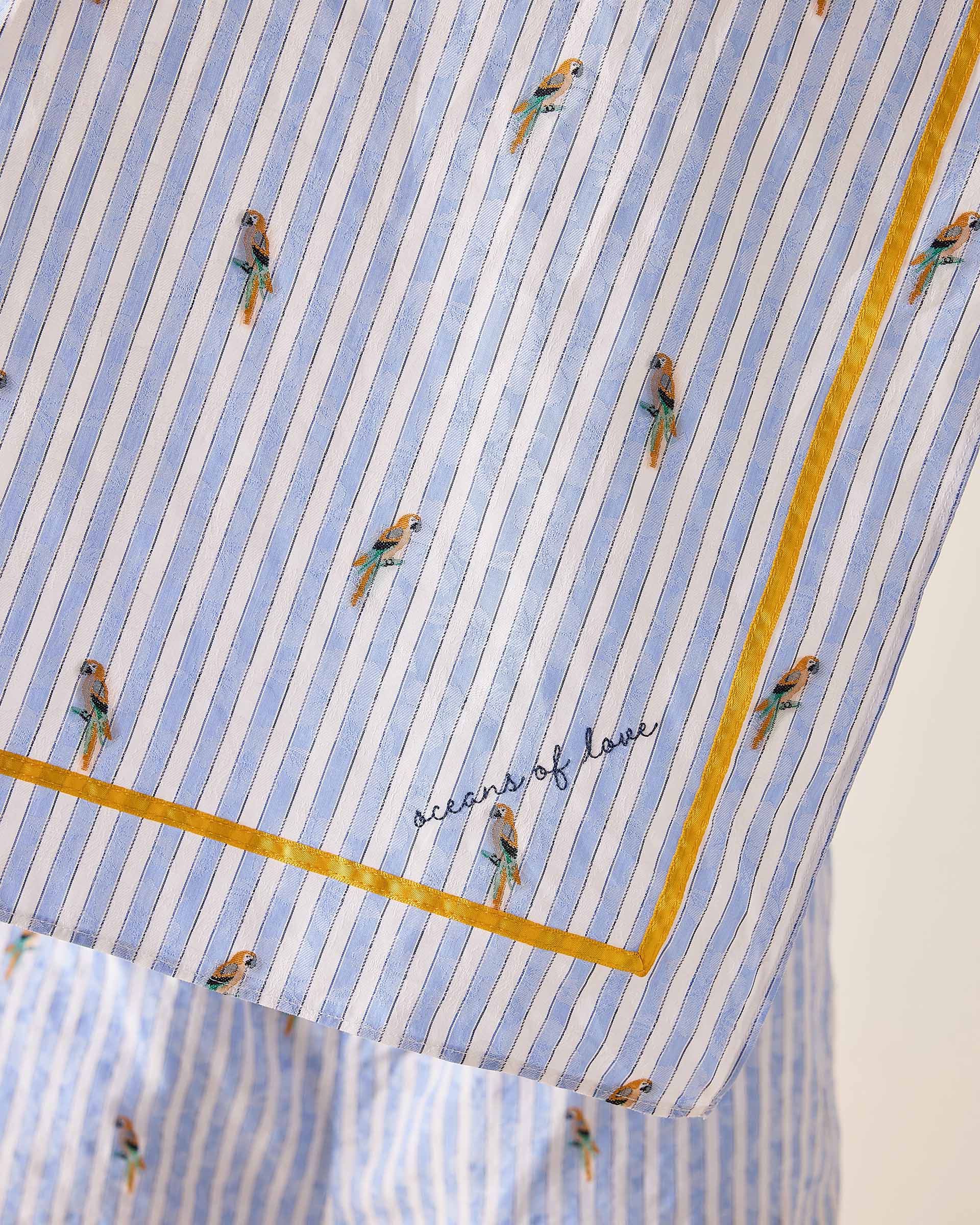 Fabric with blue and white striped pattern and small embroidered figures, featuring the brand 'Oceans of Love'.