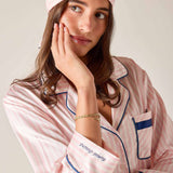 Woman wearing pink striped pajamas with a matching headband, posing thoughtfully.