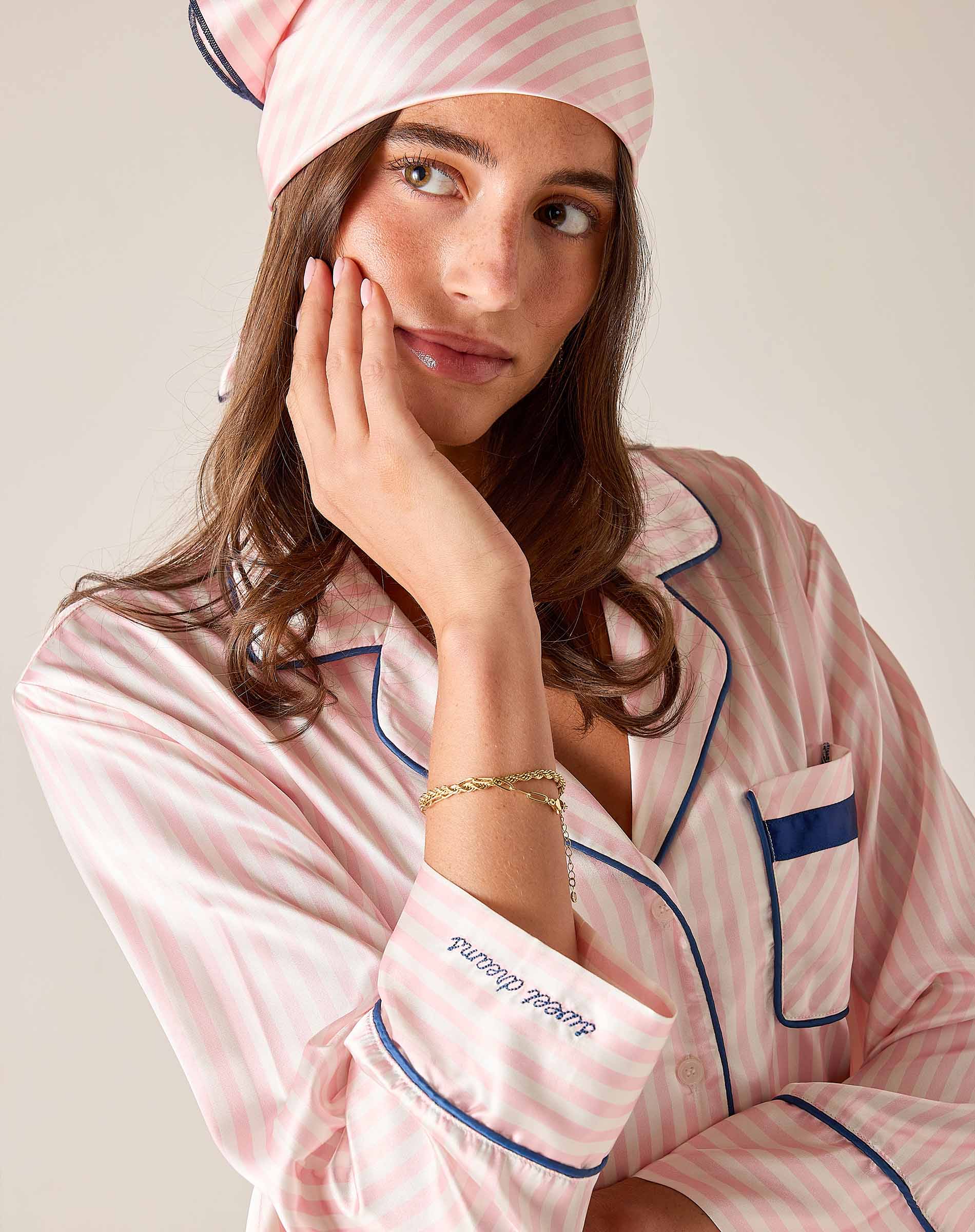 Woman wearing pink striped pajamas with a matching headband, posing thoughtfully.
