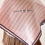 Pink striped headscarf with 'oceans of love' text on a neutral background