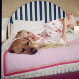 Woman in pajamas lying on a bed with a dog, wearing red lipstick.