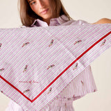 Woman holding a pink and white striped scarf with embroidered designs on a plain background