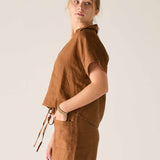 Woman wearing a brown sleeveless top and pants against a plain background