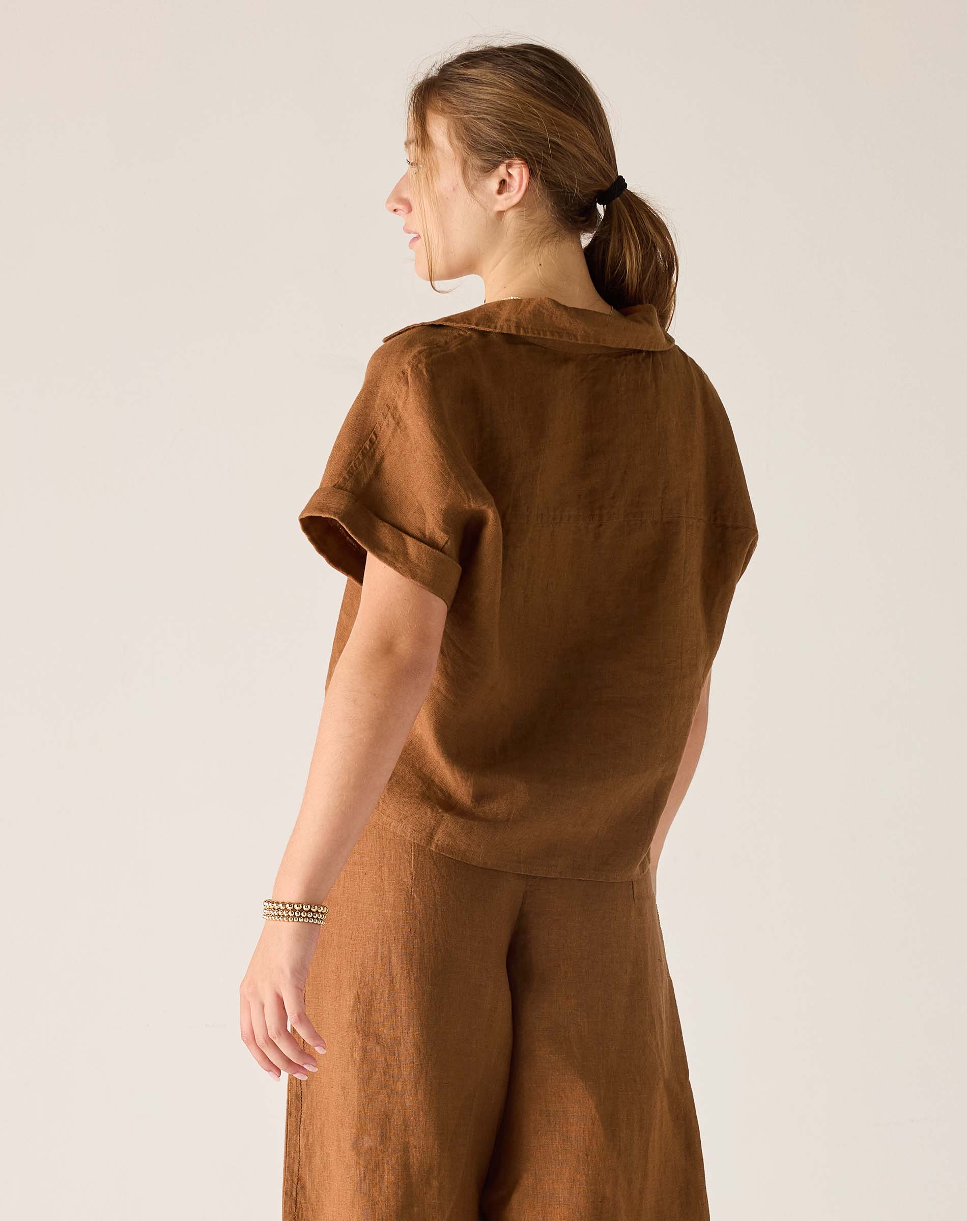 Person wearing a brown outfit against a plain background