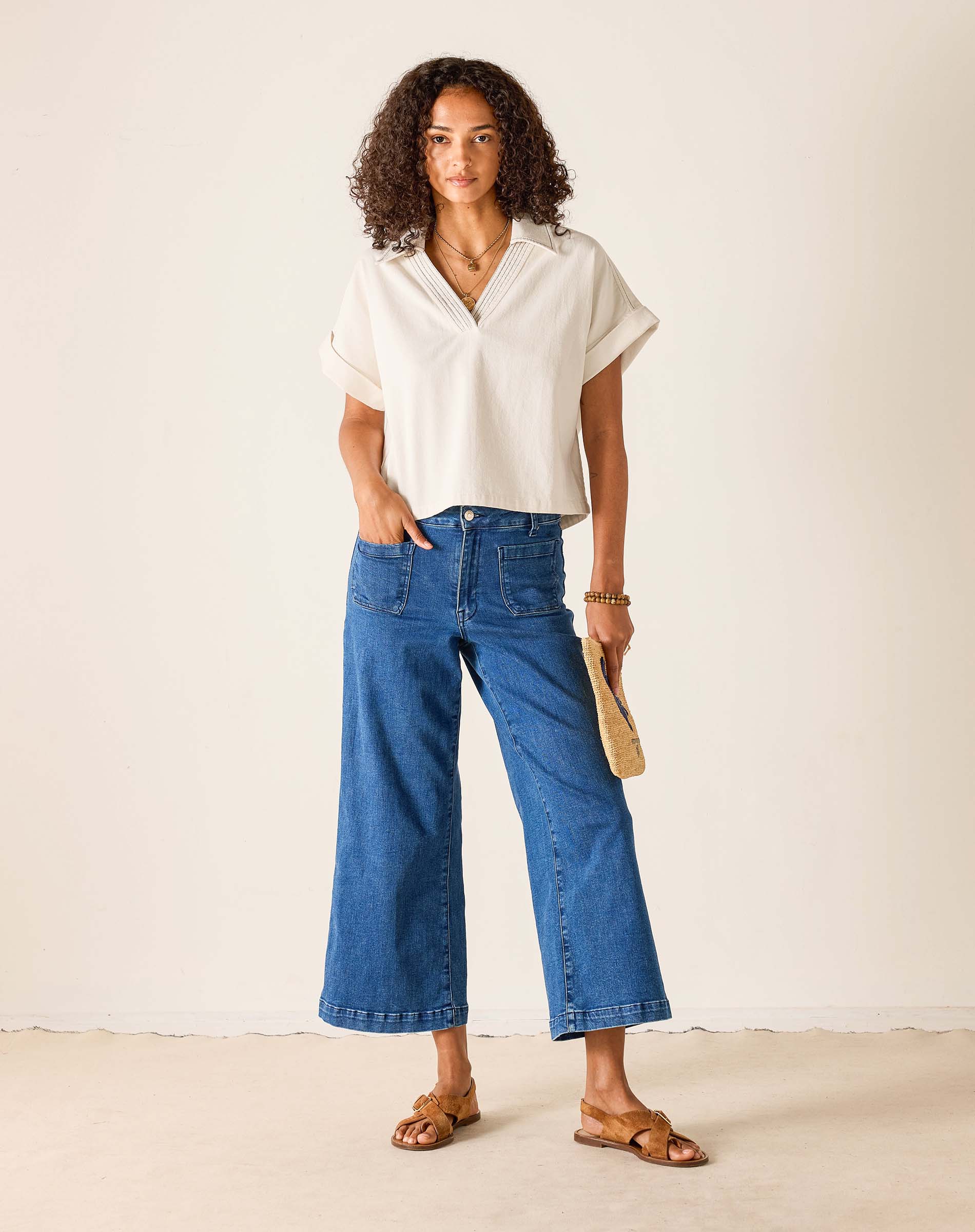 Woman wearing a white blouse and blue jeans against a plain background