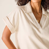 Woman wearing a beige short-sleeve shirt with a neutral background