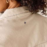 Close-up of a beige jacket with a small blue star design on the back.