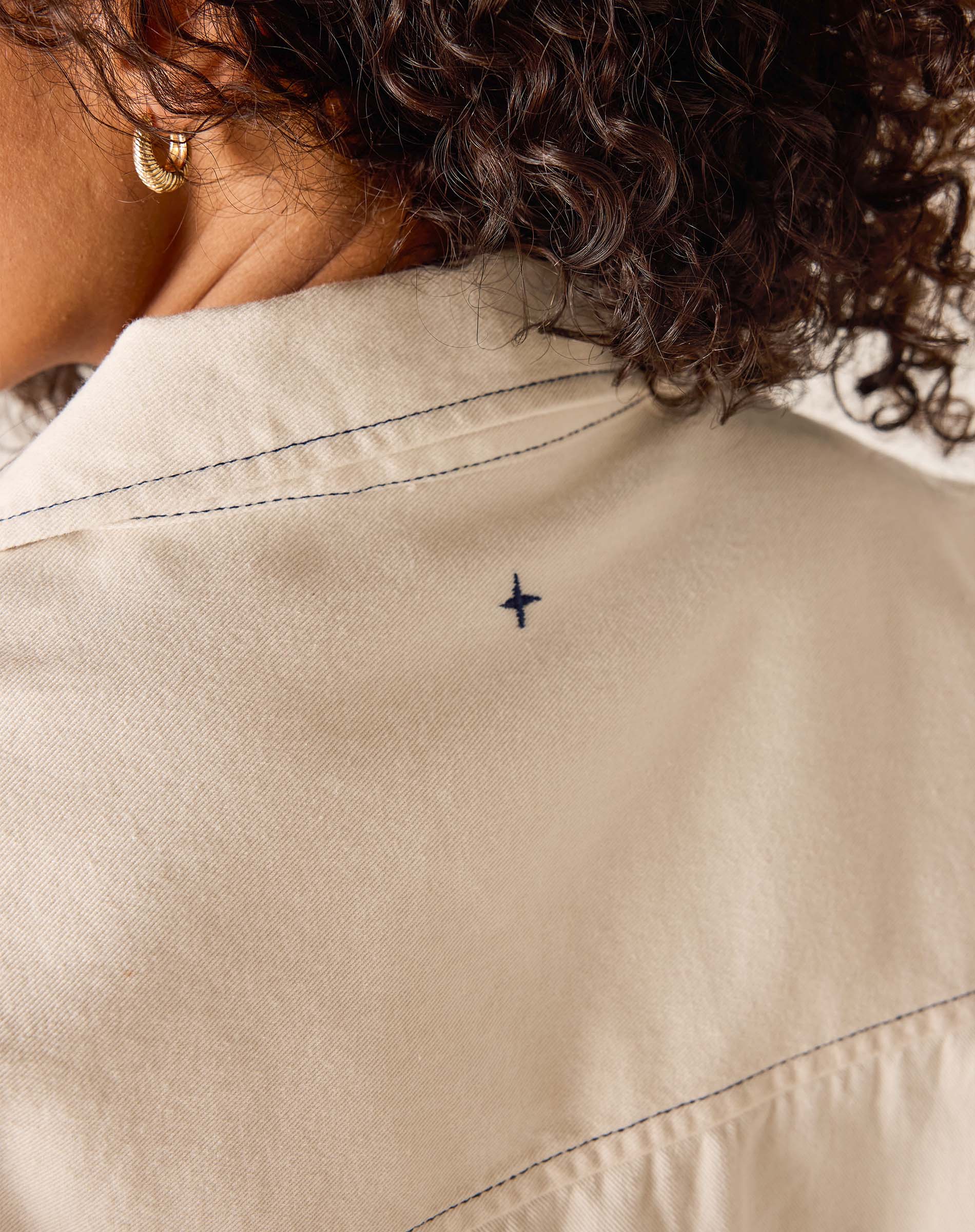 Close-up of a beige jacket with a small blue star design on the back.