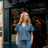 Woman in a blue outfit standing in front of a store named 'Le Repaire de'