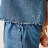 Close-up of blue denim shorts with gold stitching on a neutral background