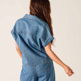 Person wearing a blue denim jumpsuit against a plain background