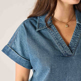 Close-up of a person wearing a blue denim shirt with a neutral background