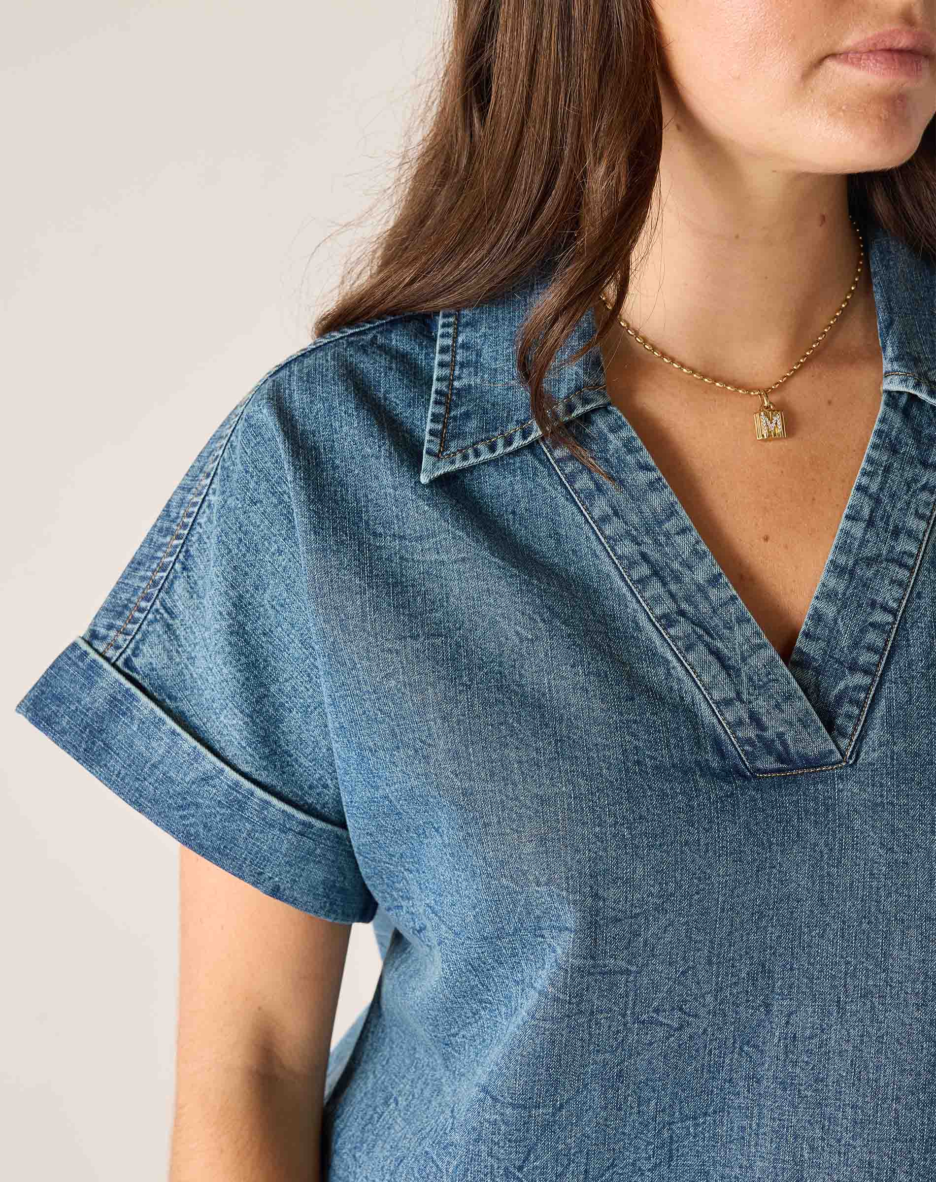 Close-up of a person wearing a blue denim shirt with a neutral background
