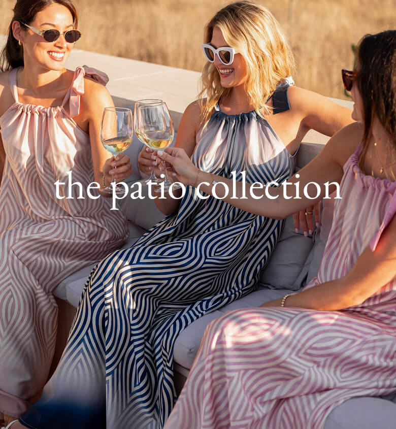 The Patio Collection - Image of three women sitting on a patio wearing different colors of a striped maxi dress