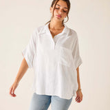 Woman wearing a white oversized shirt and light blue jeans against a plain background