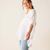 Woman wearing a white blouse and light blue jeans against a plain background