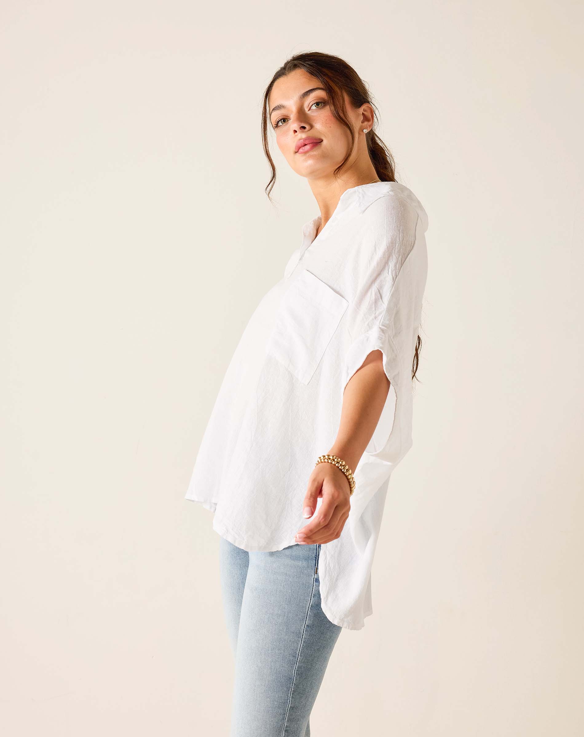 Woman wearing a white blouse and light blue jeans against a plain background