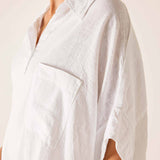 White linen shirt worn by a person on a plain background