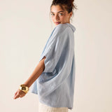 Woman wearing a light blue oversized shirt against a plain background