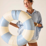 Woman holding a large inflatable ring with blue and beige colors against a plain background