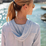 Woman wearing a light blue hoodie with a blurred natural background
