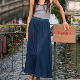Woman holding a woven bag with 'Nerea' branding by a canal.