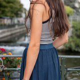 Woman wearing a striped top and blue skirt with a blurred background