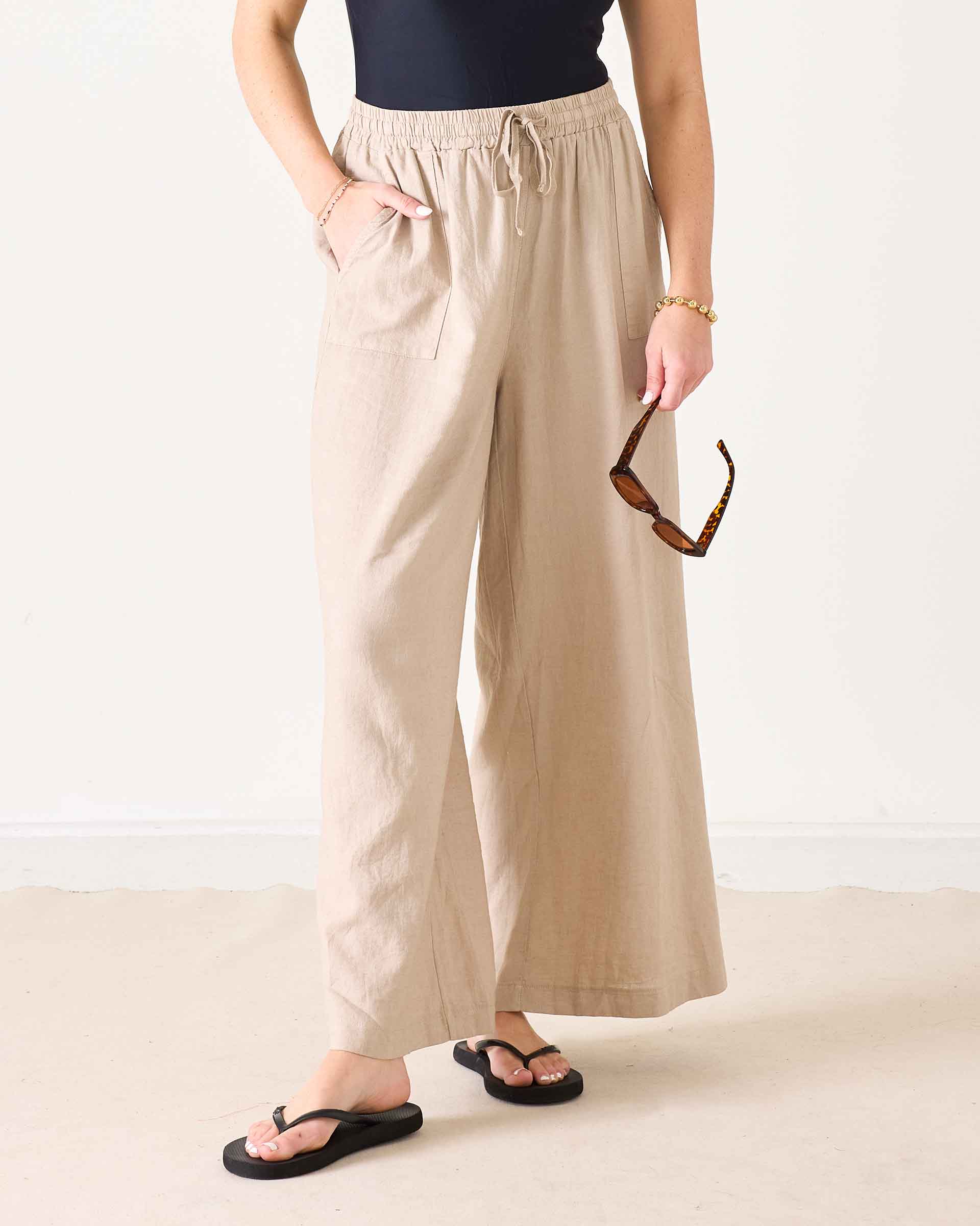 Person wearing beige wide-leg pants on a plain background