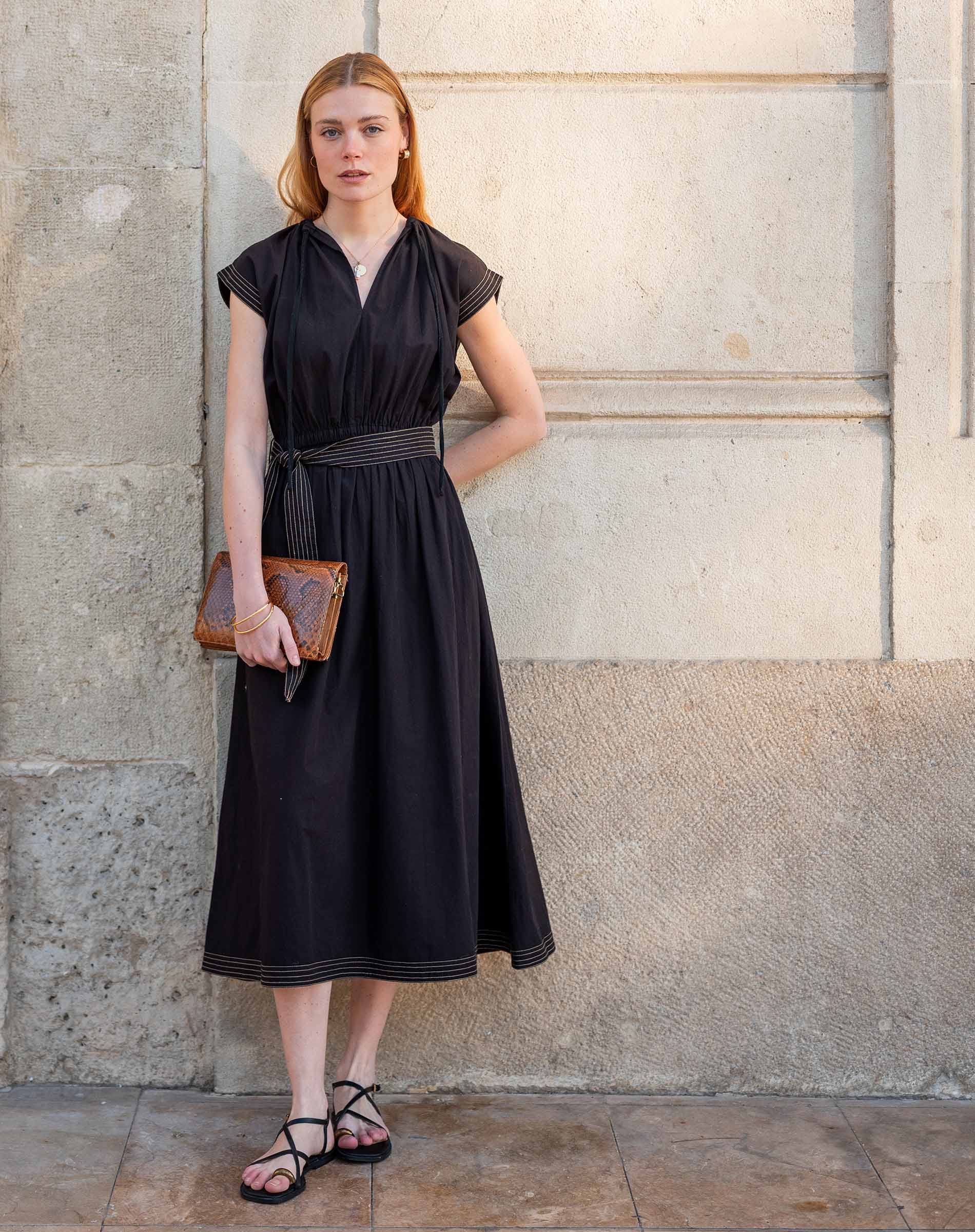 Black pleated midi dress with short sleeves and belt detail.