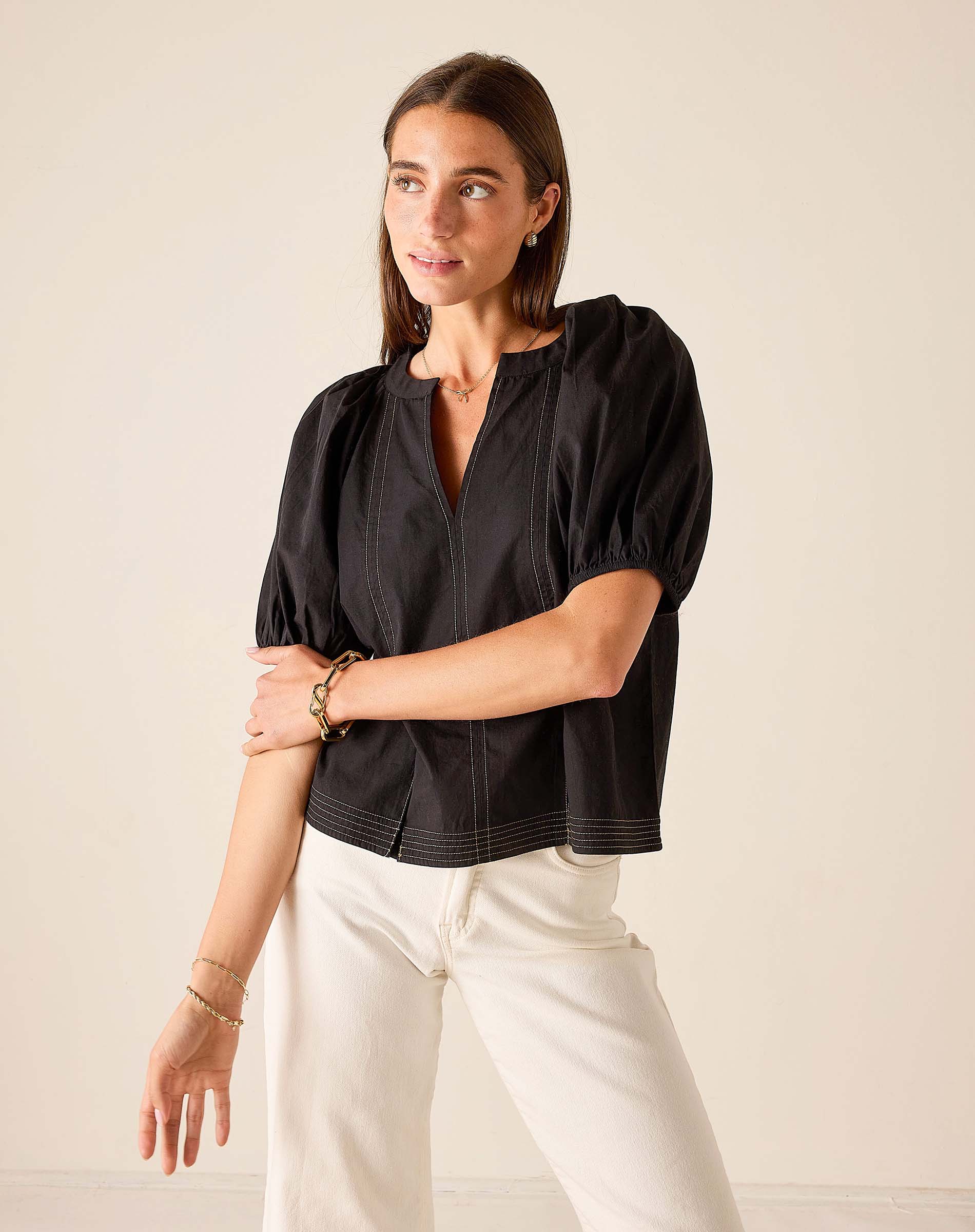 Black puff-sleeved woven cotton blouse with button front and textured detail.