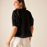 Back view of women's travel-friendly black puff-sleeve top with contrast stitching.