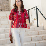 Crimson striped blouse with flutter sleeves and a ruffled placket detail.