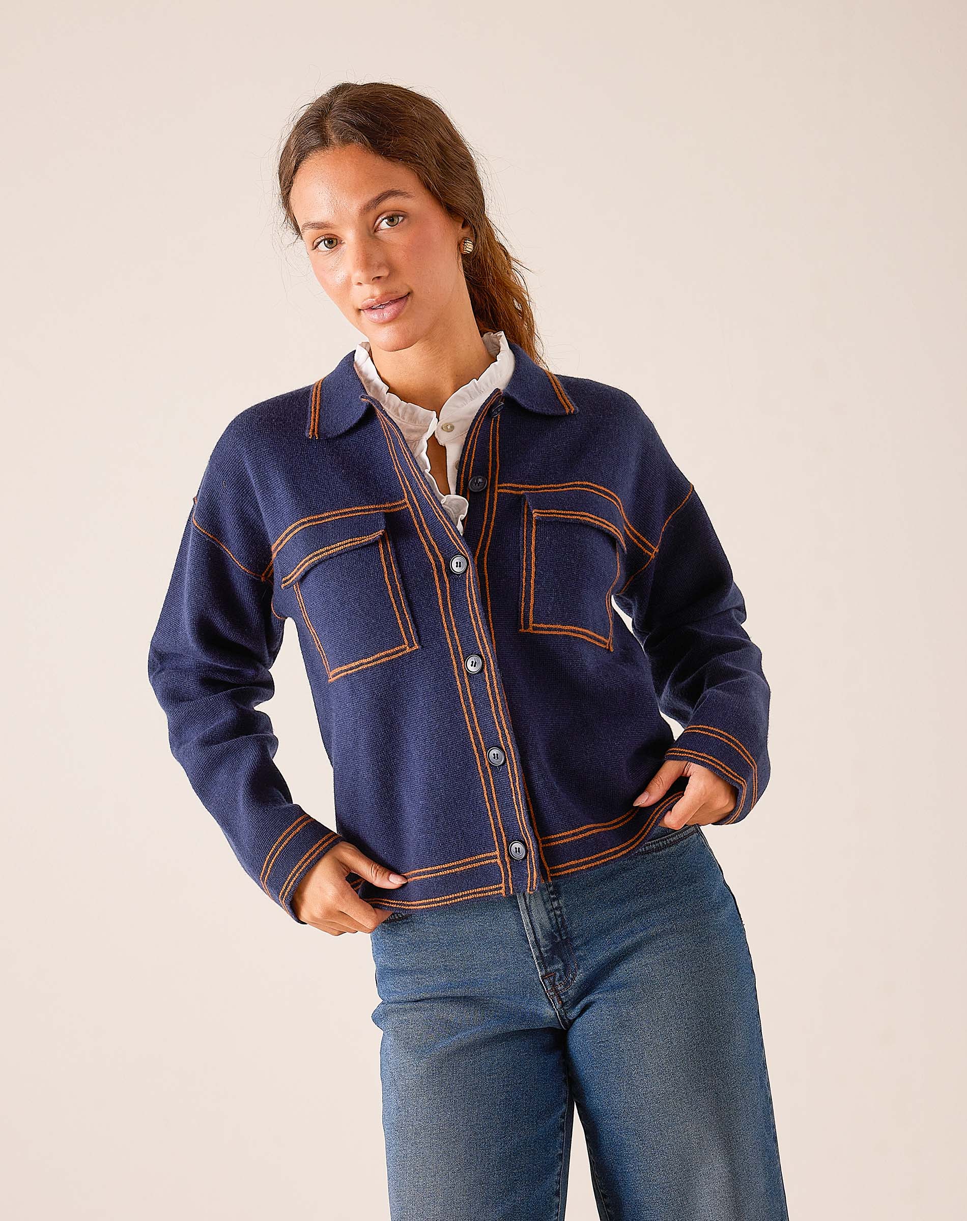 Navy blue button-front knit jacket with ochre contrasting stitching and front pockets.